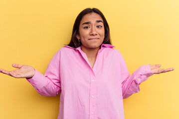 Wall Mural - Young mixed race woman isolated on yellow background doubting and shrugging shoulders in questioning gesture.