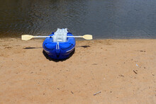 Blue Rubber Boat And Oars On The Sandy Bank Of The River. Inflatable Boat 