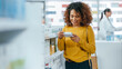 © Gorodenkoff - Pharmacy Drugstore: Beautiful Black Young Woman Walking Between aisles and Shelves with Medicine, Choosing to Buy Medicine, Drugs, Vitamins, Health Care Beauty Products with Modern Package Design