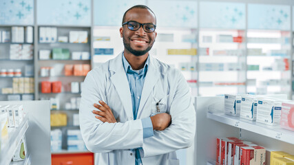 Wall Mural - Pharmacy: Professional Confident Black Pharmacist Wearing Lab Coat and Glasses, Crosses Arms and Looks at Camera Smiling Charmingly. Druggist in Drugstore Store with Shelves Health Care Products