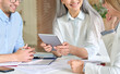 © insta_photos - Cheerful senior older mid age ceo businesswoman executive manager teacher holding using digital tablet device sitting training younger colleagues interns trainees students. Close up cropped shot.