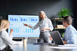 © insta_photos - Mid age senior Asian business woman ceo executive manager showing to colleagues team income revenue data figures planning on big screen in modern office on business seminar workshop.