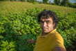 © Dip Photography - Young man farmer in a cotton farm taking selfie using a smartphone or camera.