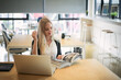 © FotoArtist - Smiling woman using laptop in work place for small businesses looking to engage audiences and scale content creation can adopt new marketing technology in workspace. Freelancer concept.