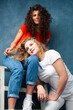© iordani - young pretty teenage girls friends with blond and brunette curly hair posing cheerful on blue background, lifestyle people concept