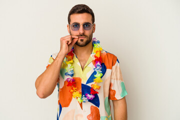 Wall Mural - Young caucasian man dancing on a hawaiian party isolated on white background with fingers on lips keeping a secret.