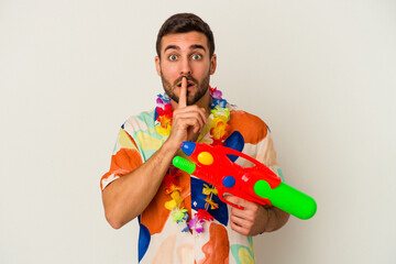 Wall Mural - Young caucasian woman on a hawaiian party holding a water gun isolated on white background keeping a secret or asking for silence.