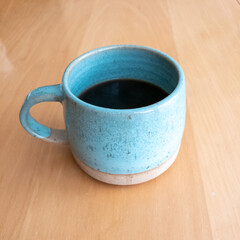 A beautiful ceramic blue coffee mug filled with coffee