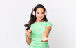 pretty hispanic woman smiling happily with friendly and offering and showing a concept with headphones and a smartphone