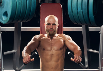 Wall Mural - Strong young man working out on a chest press machine