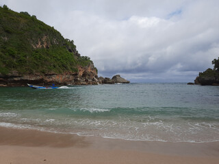 Lagoon view from sand beach to the sea, flanked from two green hills.