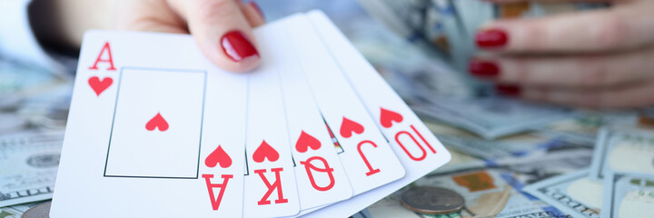 Woman holding dollar bills and playing cards in her hands