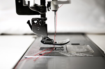 Wall Mural - Closeup of a sewing machine. Sewing needle and red cotton