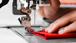 Woman's hands with red fabrics at sewing machine. Self made clothes concept.Hobby concept. Clothes repairing concept.