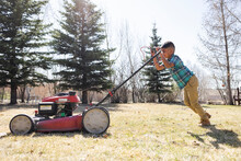 Portrait Of Boy Mowing Lawn In Backyard