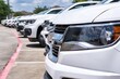 White generic fleet SUVs parked in lot, side closeup front of vehicle focus on foreground. Transportation and logistics industry.