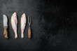 Raw surmullet  whole seafood fish, with ingredients and herbs, on black dark stone table background, top view flat lay, with copy space for text