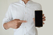 © Studio-K - 白いシャツを着た男性がスマートフォンを持っている。