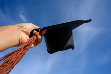 Wall Mural - University graduates hold a black hat,yellow tassels at the graduation ceremony	
