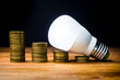 © The Cuevax - Stacks of coins with led spotlight above, electricity consumption, price reduction.