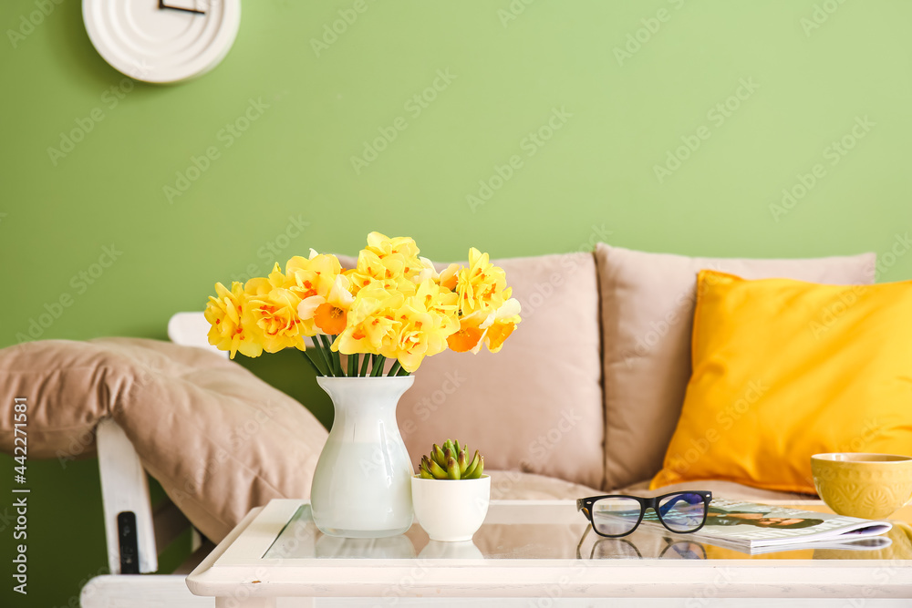 Vase with beautiful narcissus flowers on table in room
