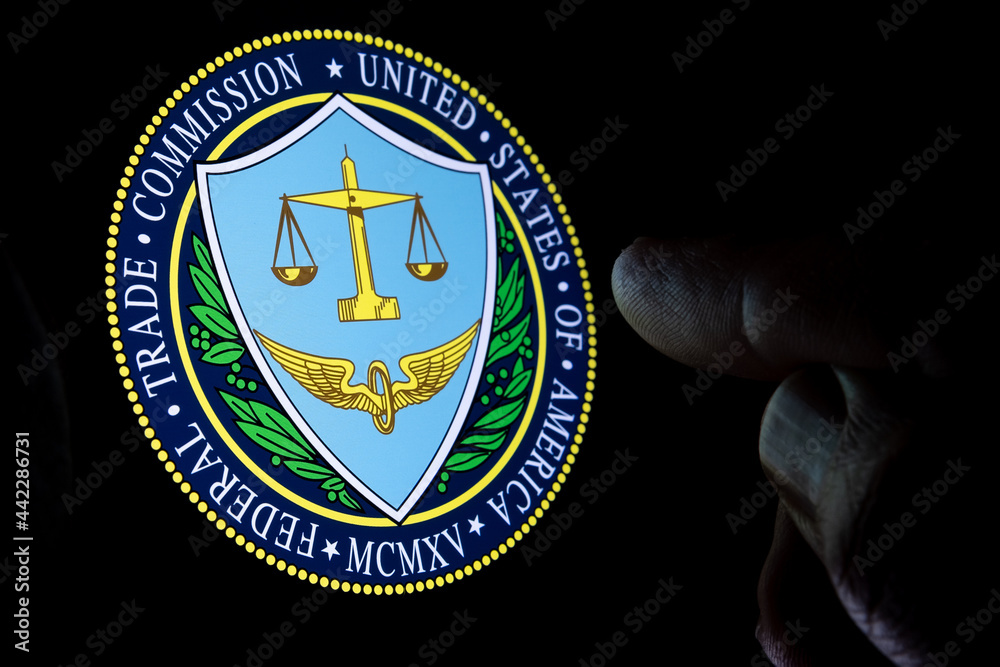 FTC Federal Trade Commission of the United States of America logo seen on the display in a dark room and blurred finger pointing at it. Concept. Stafford, UNITED KINGDOM, JULY 29, 2021.