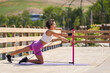 Strong woman doing exercises with portable and elastic pilates exercise stick for full body workout near by the lake