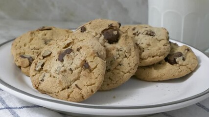 Wall Mural - Taking a crisp chocolate chip cookie from a plate slow motion
