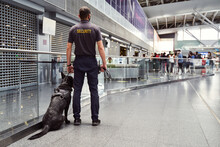 Security Worker With Detection Dog Patrolling Airport Terminal