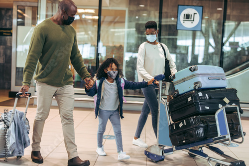 African family of three walking with luggage at airport