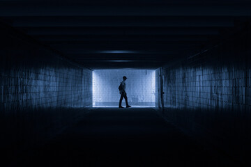 Wall Mural - dark underground passage with a silhouette of a man in profile in cold colors.