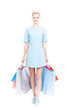 © Mediaphotos - Studio portrait shot of stylish young Caucasian woman wearing blue dress holding shopping bags, white background