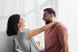 © LIGHTFIELD STUDIOS - positive young couple looking at each other and hugging in kitchen