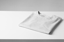Basic Folded White Tshirt On Grey Table. Mock Up For Branding T-shirt. Monochrome Trend. 