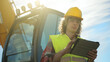 © M-Production - Excavator operator in hard hat using tablet pc.
