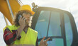 © M-Production - Excavator operator in hard hat talking by smartphone.