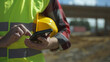 © M-Production - Builder with hard hat and high vis jacket using smartphone. Close-up.