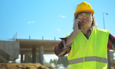 Builder talking by smartphone at construction site.