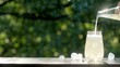 Making drinks outdoors. Hand pours a carbonated drink into a transparent glass with ice. Little splashes fly to the sides from a highly carbonated drink. Many ice cubes in a glass and around