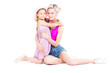 © Mediaphotos - Horizontal studio portrait of happy mother and her cute daughter wearing summer outfits sitting on floor hugging each other looking at camera