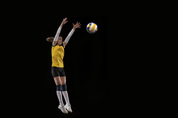 Female professional volleyball player with ball isolated on black studio background. The athlete, exercise, action, sport, healthy lifestyle, training, fitness concept.