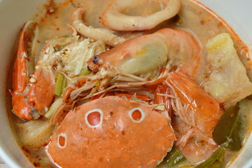 boiled flower crab and shrimp couple squid with do;;y fish in Thai spicy soup or seafood tom yum on bowl
