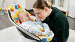 © Kyrylo Ryzhov - Happy smiling mother playing with her little baby son sitting in electric rocking chair at home. Child development and happy parenting