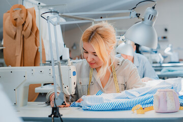 Wall Mural - Woman tailor working at the sewing behind the machine