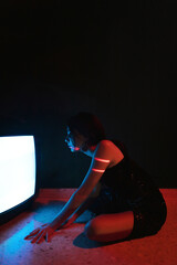 Woman sitting near old television in darkness
