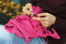 Hands Of Woman Knitting A Pink Sweater While Sitting On Park Bench In Autumn