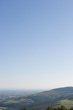 Vertical Shot Of A Hill Covered By Vegetation Under Cleer Blue Sky