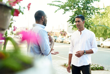 happy two multiracial male best friends talking while standing in the street, african guy talking to