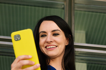 Portrait of a young adult woman using her smartphone in the office. business concept