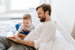 © Drobot Dean - White father and son reading book while lying on bad at home